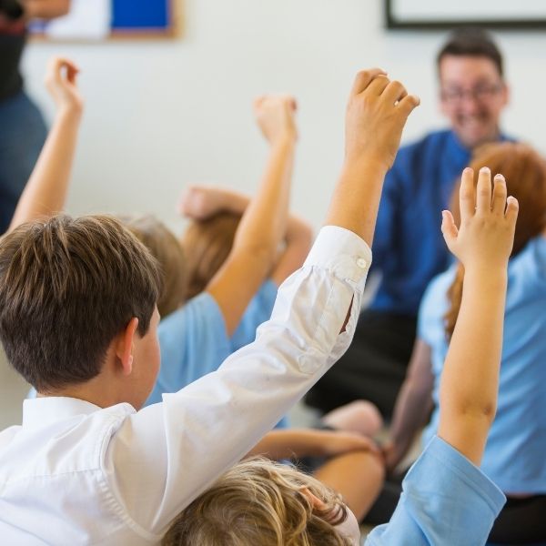 children in class with hands raised.jpg