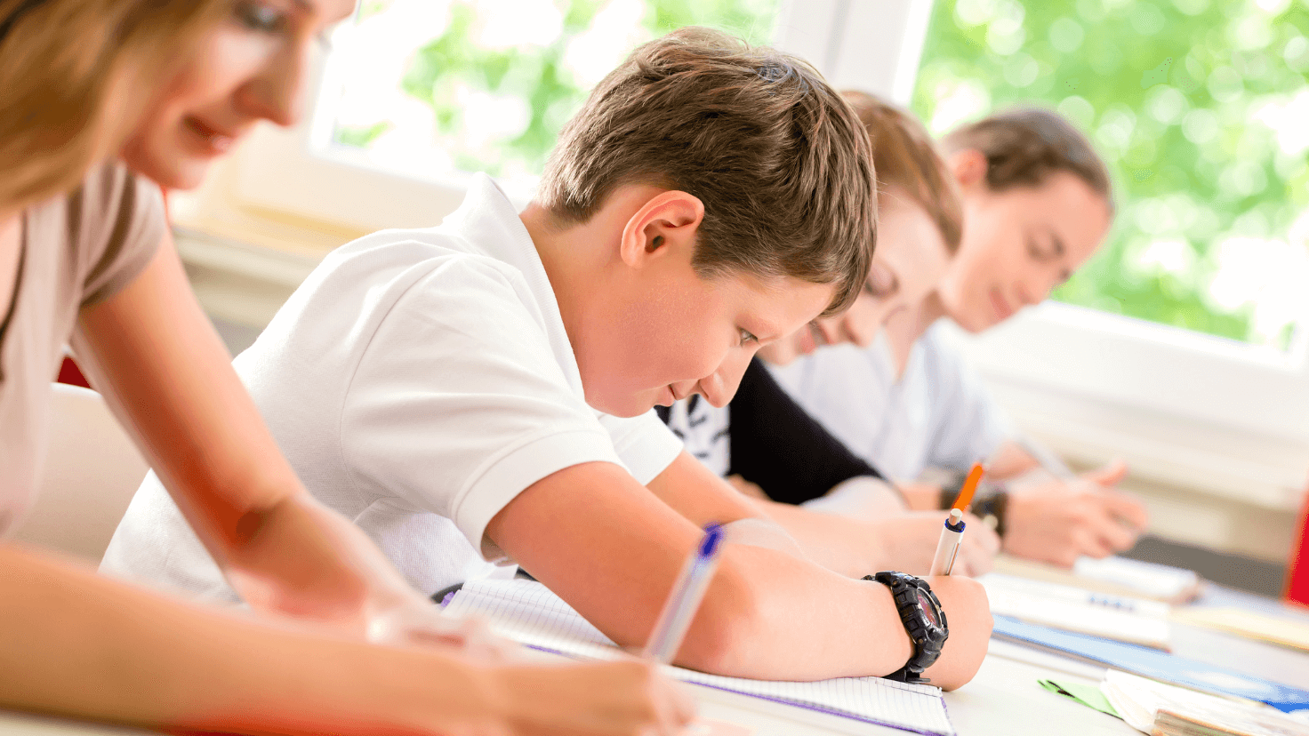 Children writing on a table with exercise books