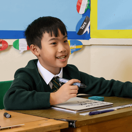 A boy sitting at the table with a pen in his hand