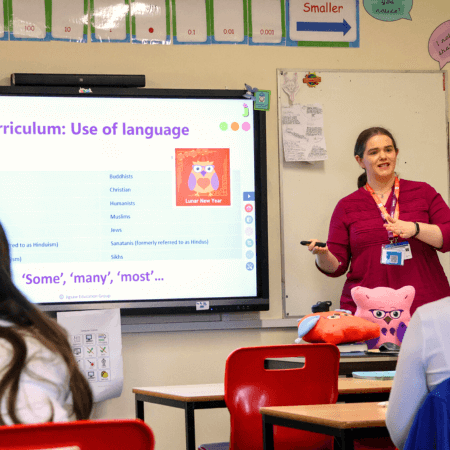 A teacher teaching at the front of a whiteboard