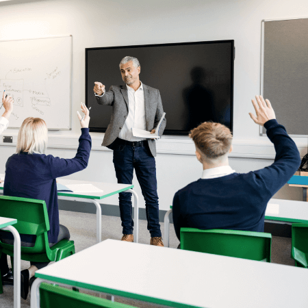 Pupils in classroom with hands up