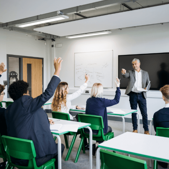 Pupils in classroom with hands up